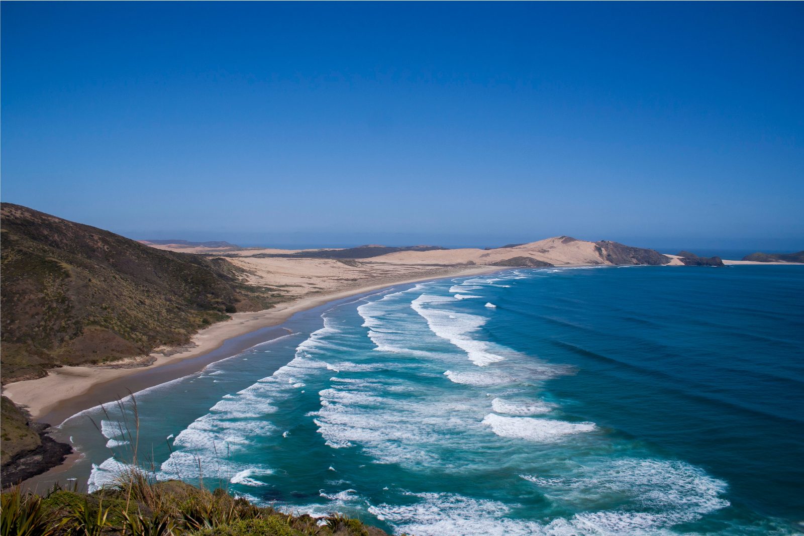 Dramatic volcanic rock faces towering over the coastline provide a unique windbreak for surfers. These 600-meter-high formations are a signature landmark of the region.
